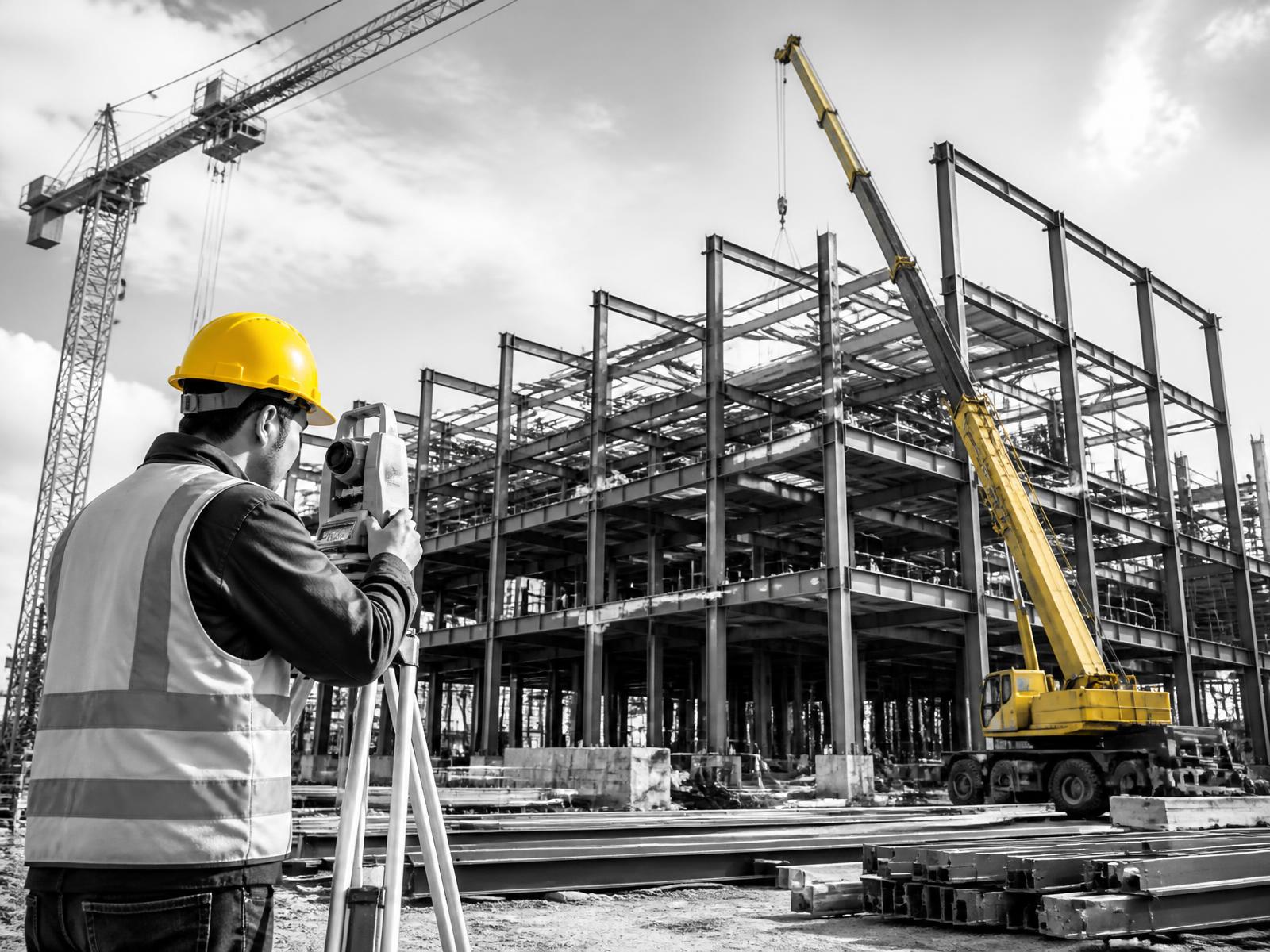 Site engineer surveying a steel-frame construction project